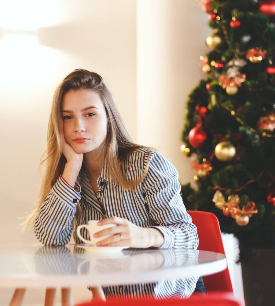young-beautiful-woman-drinks-hot-coffee-in-cafe-with-christmas-tree-decorations-1.jpg